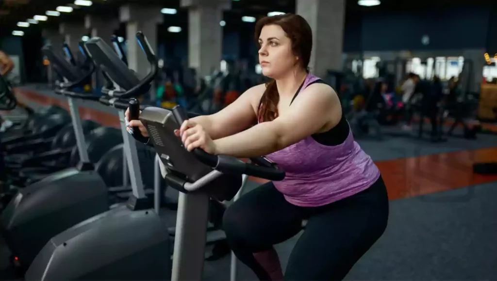 تصویری از خانمی با اضافه وزن شدید در حال دوچرخه زدن ثابت